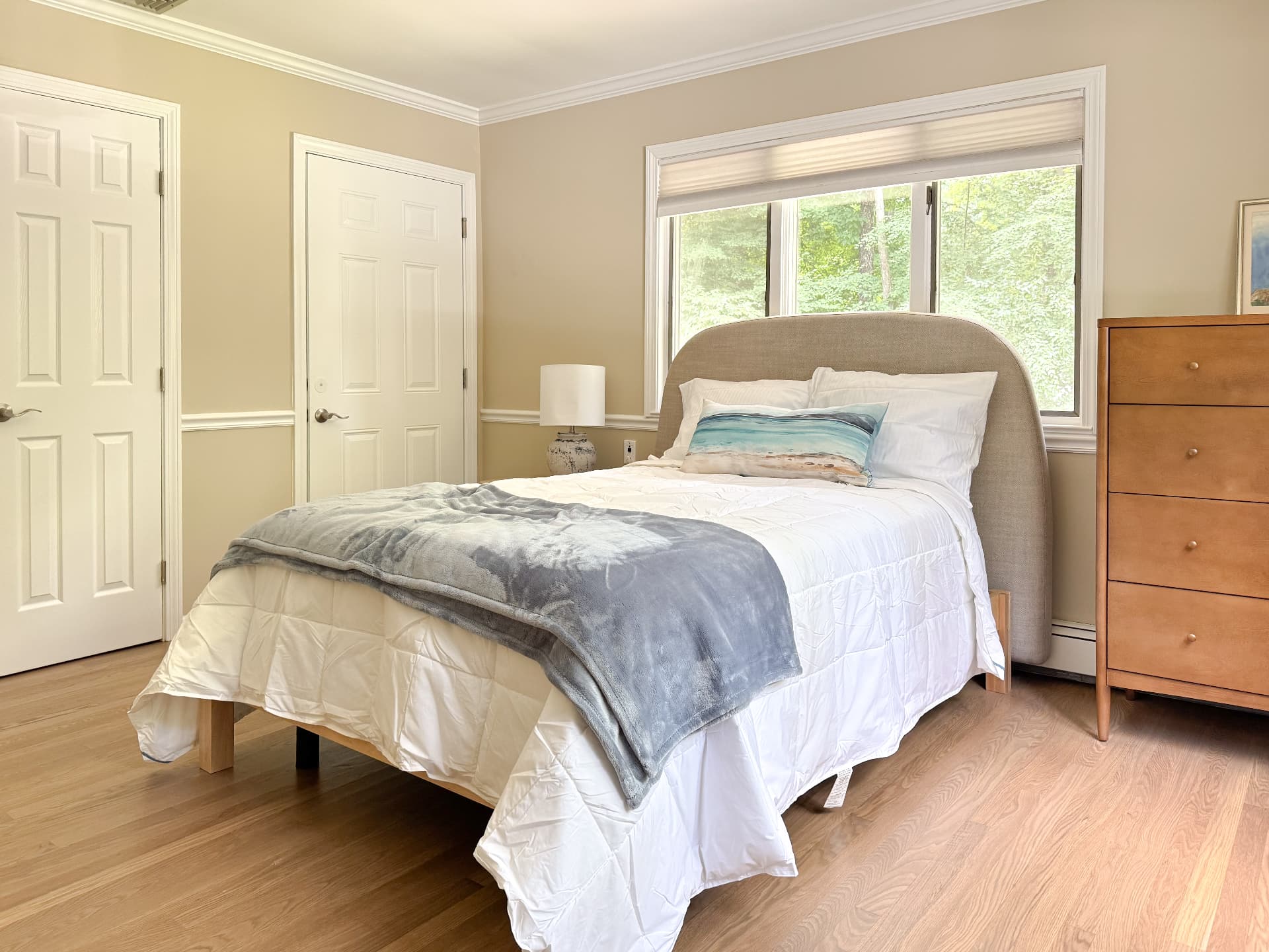 A calm, sunlit resident bedroom with woodland views